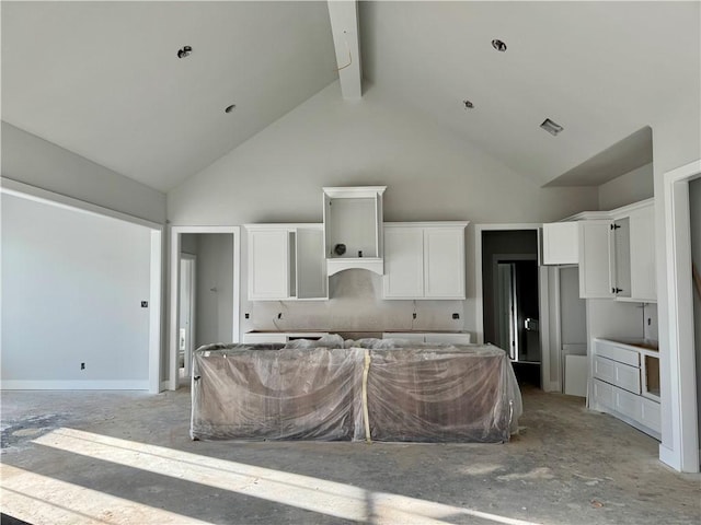 kitchen featuring high vaulted ceiling, a kitchen island, and white cabinetry