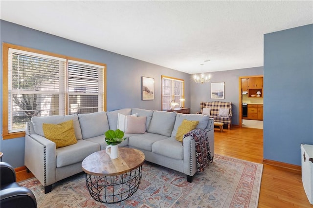 living room featuring light wood-style floors, a chandelier, and baseboards