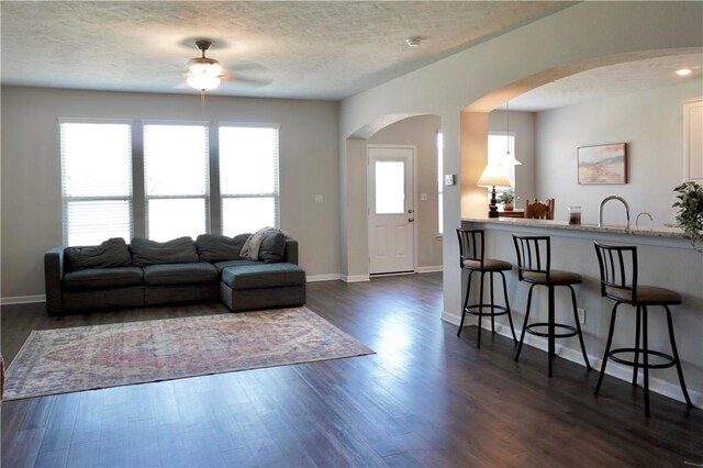 2011 Stubbs Dr, Bryan, TX 77807 - living room with ceiling fan, arched walkways, baseboards, dark wood finished floors, and a textured ceiling
