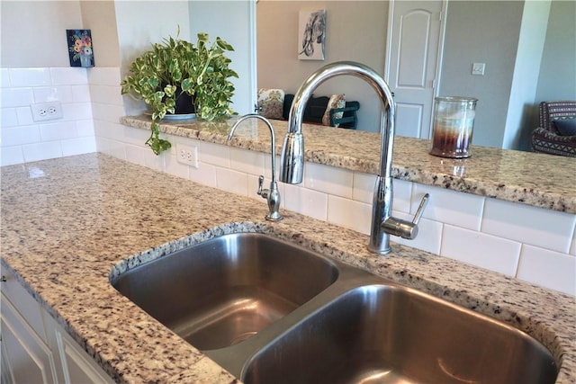 2011 Stubbs Dr, Bryan, TX 77807 - kitchen view of a sink, backsplash, light stone counters, and white cabinetry