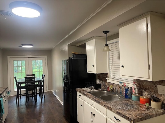 508 Victoria St, Navasota, TX 77868 - kitchen with dark wood finished floors, white cabinets, dark countertops, decorative backsplash, and ornamental molding