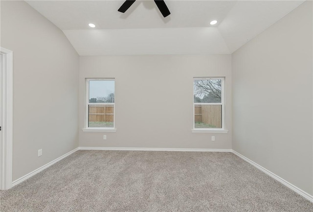 carpeted empty room with baseboards, lofted ceiling, plenty of natural light, and ceiling fan