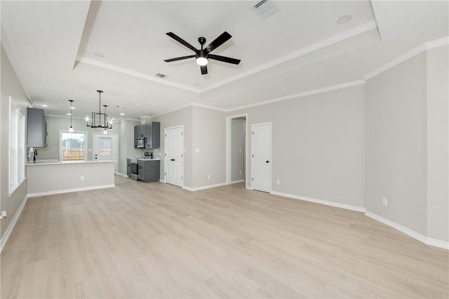 unfurnished living room featuring a raised ceiling, light wood-type flooring, visible vents, and ceiling fan