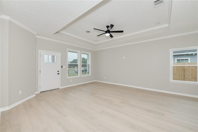 empty room featuring visible vents, baseboards, a tray ceiling, light wood-style floors, and a ceiling fan