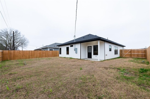 rear view of house with a yard and a fenced backyard