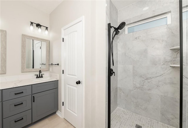 full bathroom featuring a tile shower and vanity