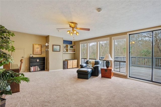 living area with a textured ceiling, carpet floors, and ceiling fan