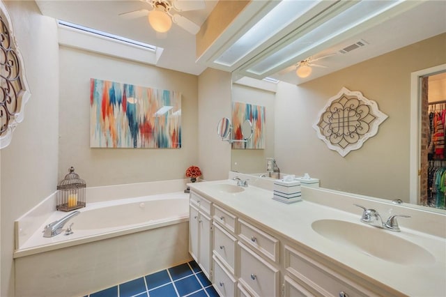 bathroom featuring tile patterned flooring, vanity, a tub to relax in, and a skylight