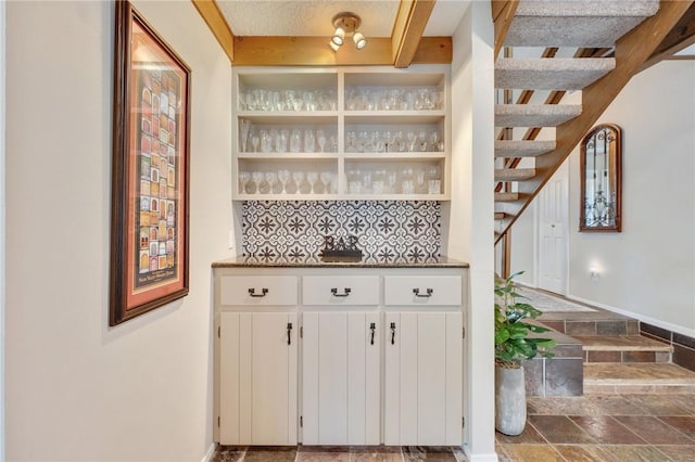 bar with white cabinets and decorative backsplash