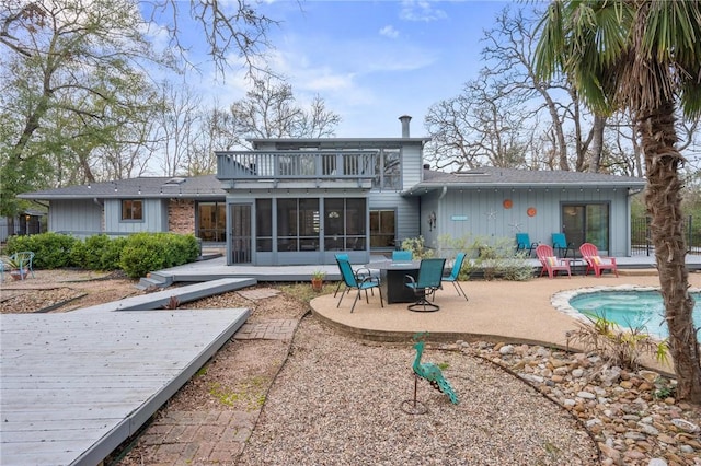 rear view of property with a patio area, a sunroom, and a balcony