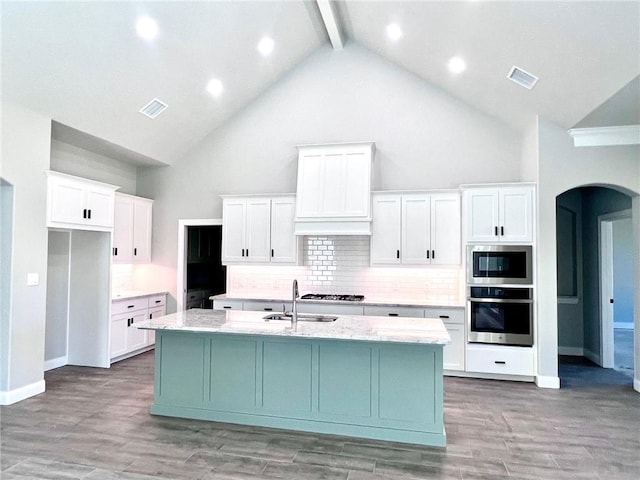 kitchen with white cabinets, a kitchen island with sink, high vaulted ceiling, and stainless steel appliances