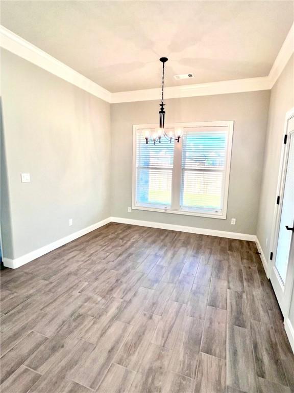 unfurnished dining area featuring hardwood / wood-style floors, a notable chandelier, and ornamental molding