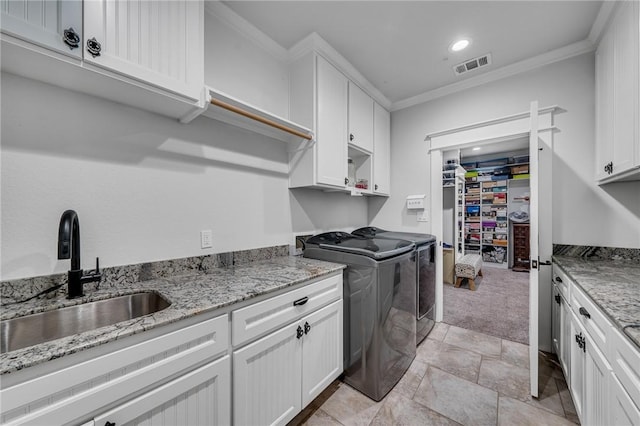 laundry area with light carpet, cabinets, crown molding, sink, and washer and dryer