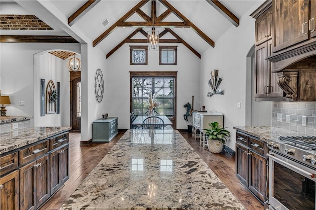 kitchen featuring high end range, decorative backsplash, decorative light fixtures, and light stone countertops