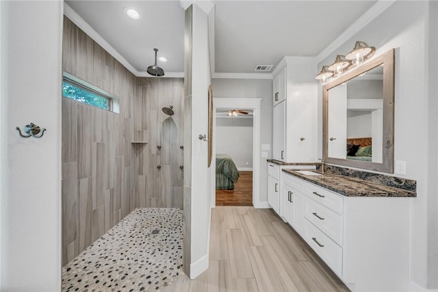 bathroom with tiled shower, wood-type flooring, vanity, and ornamental molding