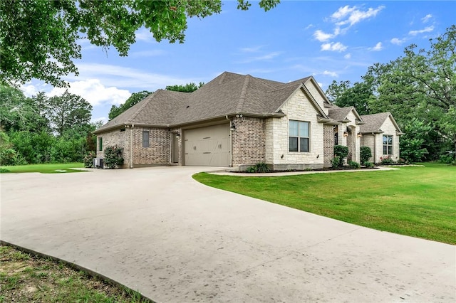 french country style house with a front yard and a garage