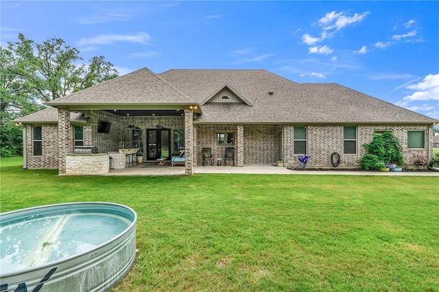 back of house with a yard, a patio, and exterior kitchen