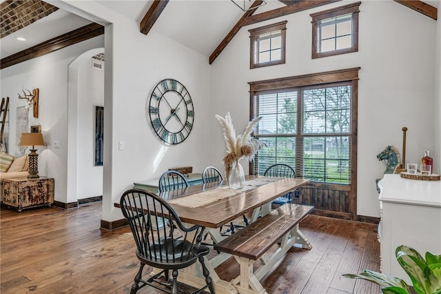 dining room featuring beam ceiling, dark hardwood / wood-style flooring, and a high ceiling