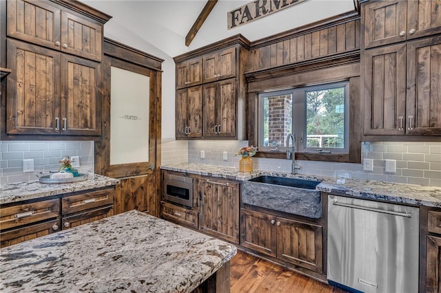 kitchen with light stone countertops, sink, tasteful backsplash, lofted ceiling with beams, and appliances with stainless steel finishes