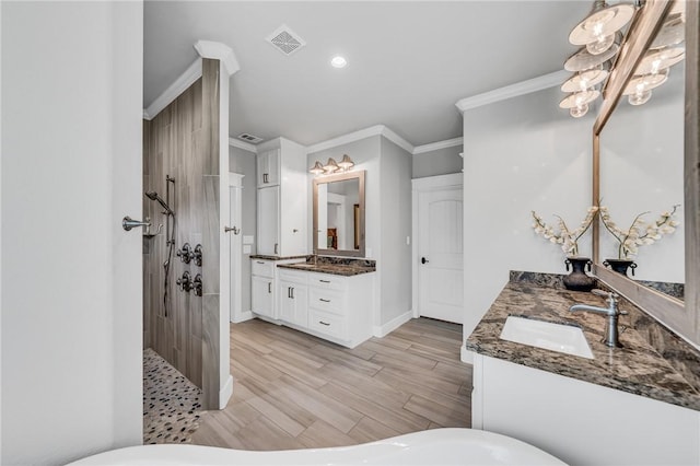 bathroom featuring a tile shower, vanity, and ornamental molding