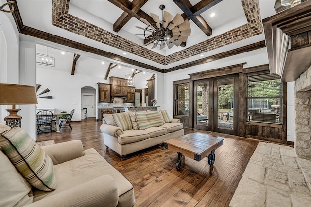 living room featuring beamed ceiling, a high ceiling, ceiling fan with notable chandelier, and dark wood-type flooring