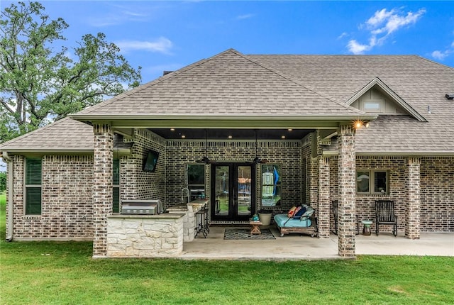 rear view of property with an outdoor kitchen, a yard, and a patio