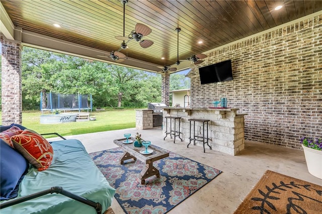 view of patio with area for grilling, ceiling fan, an outdoor bar, and a trampoline