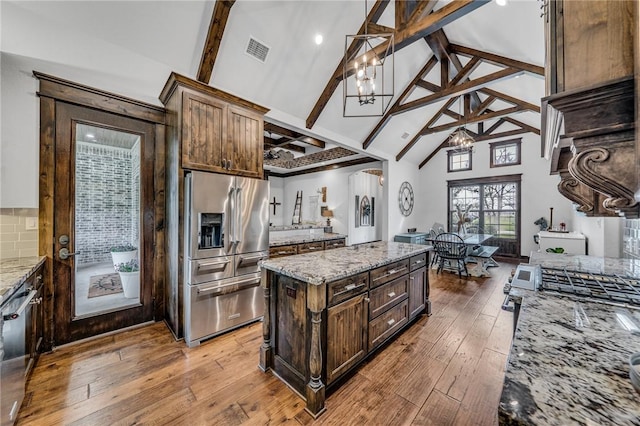 kitchen featuring light hardwood / wood-style flooring, beamed ceiling, a notable chandelier, light stone counters, and stainless steel appliances