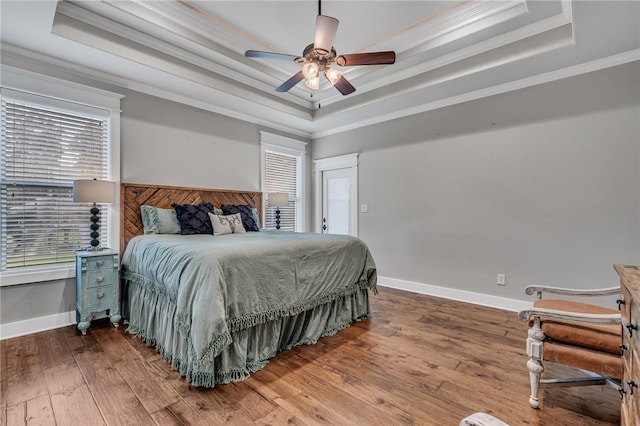 bedroom featuring hardwood / wood-style flooring, ceiling fan, a raised ceiling, and crown molding