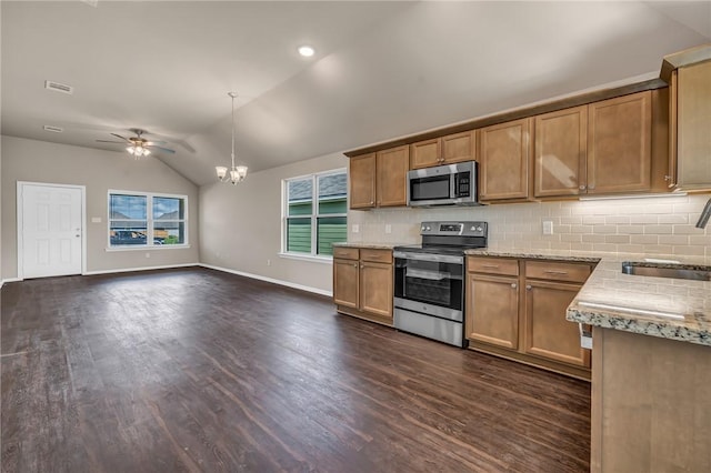 kitchen with open floor plan, a sink, lofted ceiling, decorative light fixtures, and stainless steel appliances