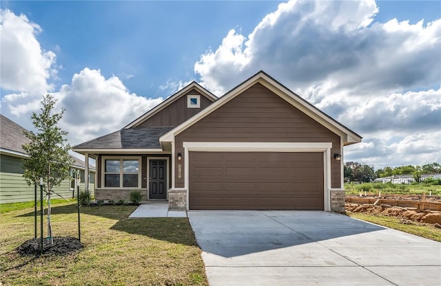 craftsman house with a front lawn, brick siding, a garage, board and batten siding, and driveway