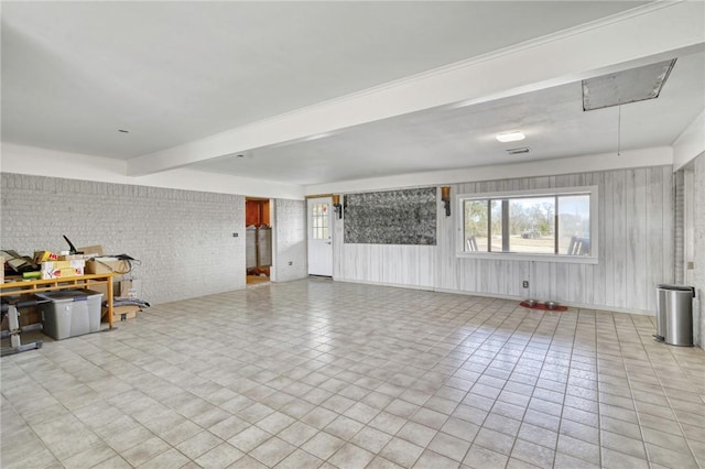 unfurnished living room with beamed ceiling, brick wall, and light tile patterned floors