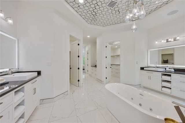 bathroom with a tub with jets, marble look tile flooring, two vanities, and a tray ceiling