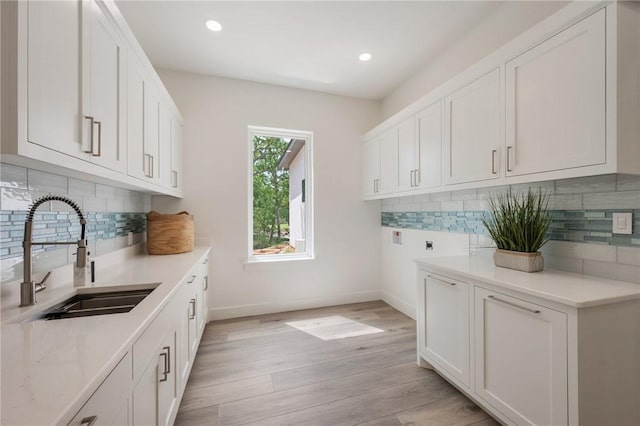 washroom with cabinet space, light wood-style flooring, baseboards, hookup for an electric dryer, and recessed lighting