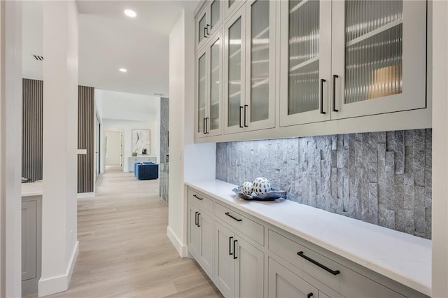 bar area featuring baseboards, light wood finished floors, decorative backsplash, and recessed lighting