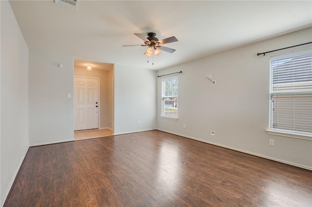 empty room with a ceiling fan, visible vents, baseboards, and wood finished floors