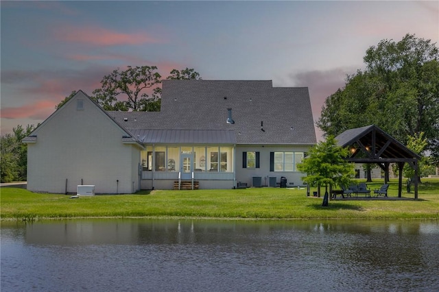 10560 St John Dr, Iola, TX 77861 - back of house at dusk featuring a gazebo, a water view, a lawn, and a standing seam roof