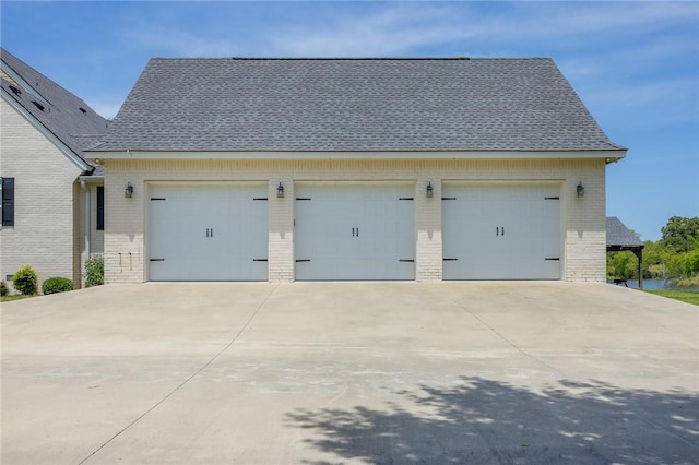 10560 St John Dr, Iola, TX 77861 - view of side of home featuring brick siding, roof with shingles, and a detached garage