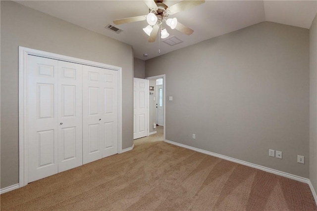 unfurnished bedroom featuring light carpet, vaulted ceiling, a closet, and ceiling fan