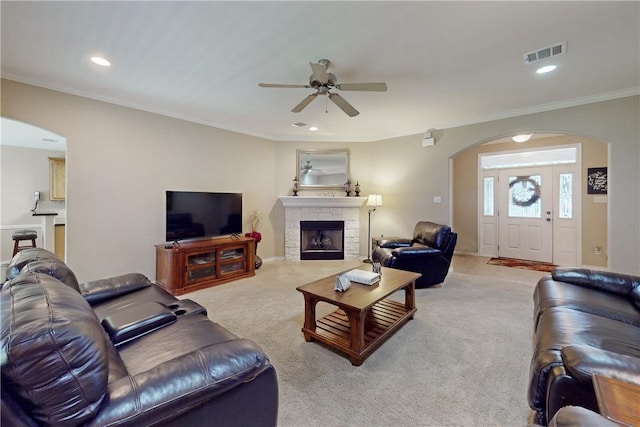 living room with crown molding, light carpet, ceiling fan, and a fireplace