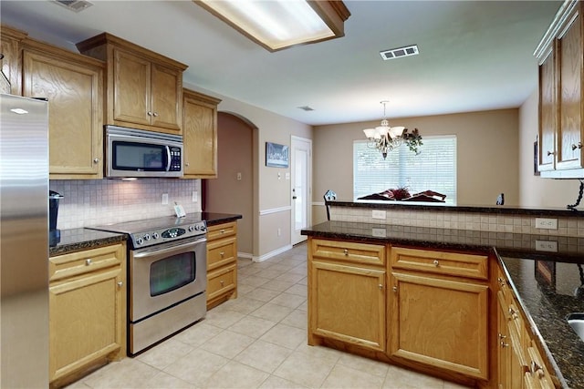 kitchen featuring decorative light fixtures, light tile patterned floors, dark stone countertops, stainless steel appliances, and decorative backsplash