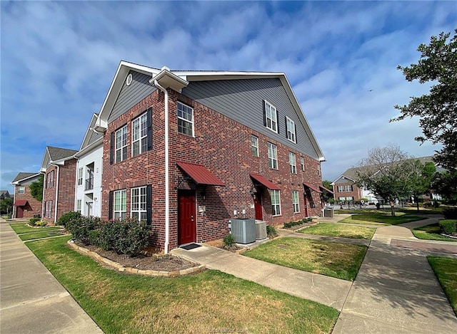 801 Luther St W Unit 401, College Station, TX 77840 - view of home's exterior featuring brick siding, a yard, a residential view, and central air condition unit