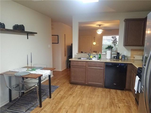 kitchen featuring dishwasher, a sink, light wood-type flooring, a peninsula, and range with gas stovetop