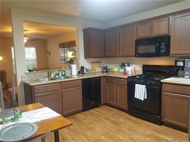 kitchen featuring light wood-style flooring, a sink, ceiling fan, light countertops, and black appliances
