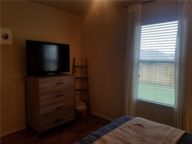 bedroom with dark wood-style flooring, multiple windows, and baseboards