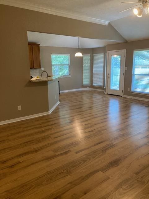 2704 Barronwood Dr, Bryan, TX 77807 - unfurnished living room featuring ceiling fan, crown molding, baseboards, wood finished floors, and lofted ceiling