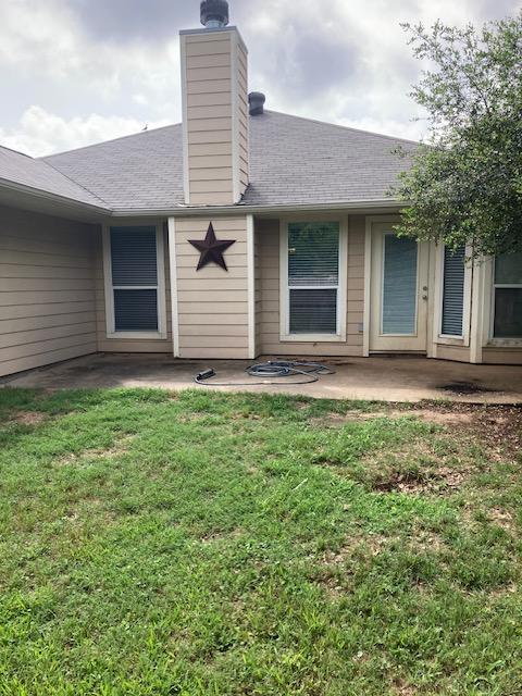 2704 Barronwood Dr, Bryan, TX 77807 - doorway to property featuring a patio area, a lawn, a chimney, and roof with shingles