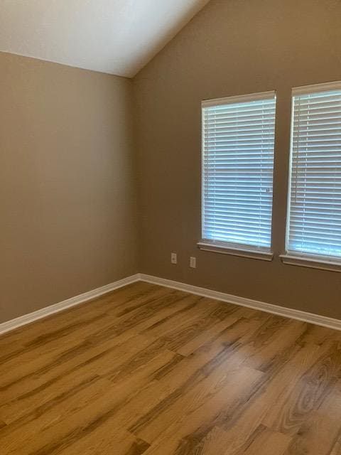 2704 Barronwood Dr, Bryan, TX 77807 - empty room with wood finished floors, vaulted ceiling, and baseboards