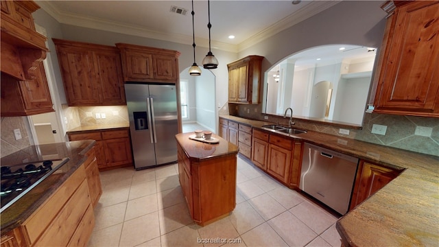 kitchen featuring sink, stainless steel appliances, light tile patterned floors, dark stone counters, and a kitchen island