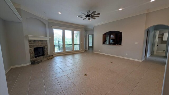 unfurnished living room featuring light tile patterned flooring, ornamental molding, baseboards, a stone fireplace, and recessed lighting
